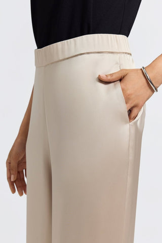 Close up of the side of the elegant satin trousers with models hand in pocket #color_champagne