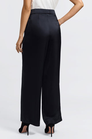 Angled back view of the satin trousers with elastic waist band #color_black