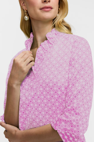 Close up anlge on the ruffle collar and v-neckline of the Tammy Petite Geo Lattice 3/4 Sleeve Popover Shirt #color_pink/white geo lattice