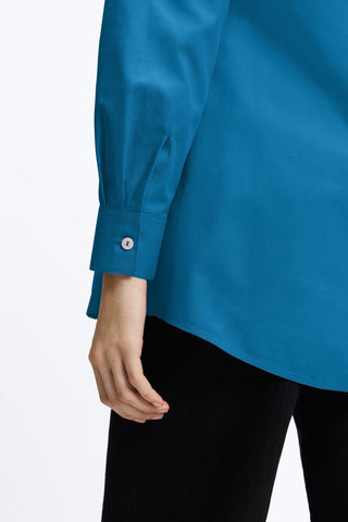 Zoomed in back view showing the finished hem and the buttoned cuff on the Cici No Iron Pinpoint Long Sleeve Tunic #color_teal