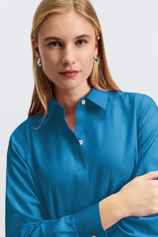 Close up view of a woman with her arms crossed wearing the Cici No Iron Pinpoint Long Sleeve Tunic showing the collar and neckline #color_teal