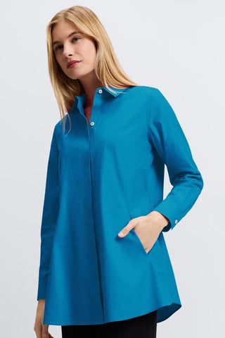 Angled front view of a woman wearing the Cici No Iron Pinpoint Long Sleeve Tunic with one of her hands in the pocket #color_teal