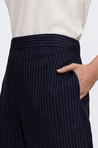 Close up on the waistband and pinstripe pattern of the linen cropped pants with models hand in functional pockets 