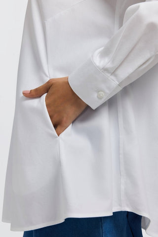 Side view of the Cici No Iron Pinpoint Long Sleeve Tunic worn by a woman with her hand in the pocket #color_white