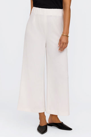 Front view of white flowy wide leg pants in front of a white background worn by a model with flats #color_ecru