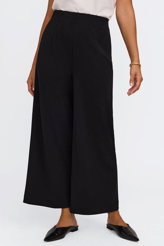 Model with popped hip wearing the flowy wide leg ankle length pants #color_black