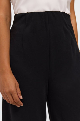 Close up on the thick waist band and pleats on the wide leg pants #color_black