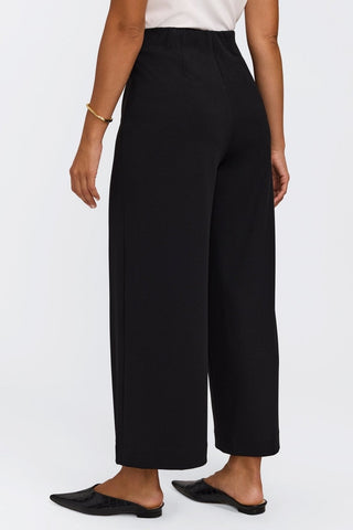Angled back view of the ankle length wide leg pants #color_black