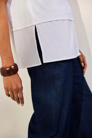 Bottom half of Sasha Knit-Woven Sleeveless Layering Tunic worn untucked with jeans #color_white
