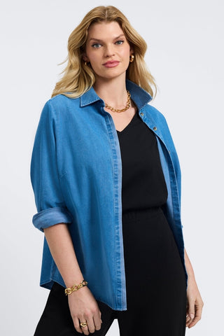 Woman in a medium denim button-front shirt from Foxcroft, designed with casual sophistication and lasting comfort.