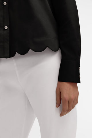 Close up of the scalloped hem and crisp cuff of the Scarlett Stretch Matte Sateen Long Sleeve Shirt #color_black