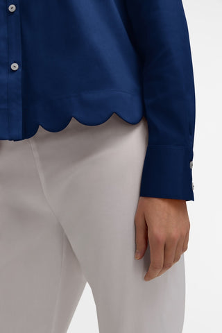 Close up of the bottom half of the Scarlett Stretch Matte Sateen Long Sleeve Shirt
showing the scalloped hem and tailored fitted sleeves #color_navy