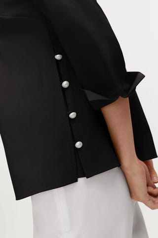 Close up of the full coverage side slit and it's pearl buttons on the Beatrice Pearl Stretch Matte Sateen 3/4 Sleeve Shirt #color_black