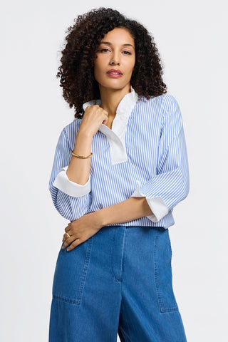 Front view of model wearing the 3/4 sleeve popover shirt tucked into jeans with closed neck #color_powder blue pinpoint stripe