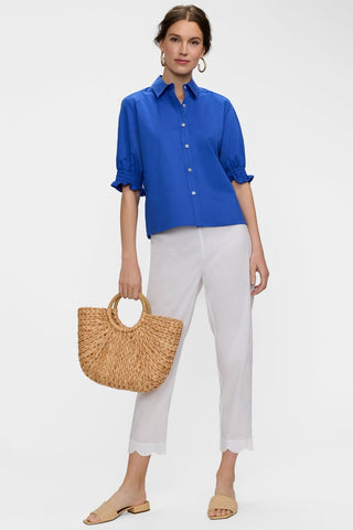 Wide angle view of scalloped satin capris worn with a button down and one of the models feet turned out #color_white