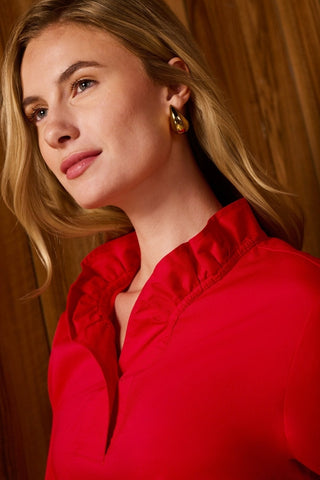 Close up of the ruffle neckline on the Tammy No Iron Stretch Long Sleeve Popover Shirt being worn in front of a wooden background #color_simply red