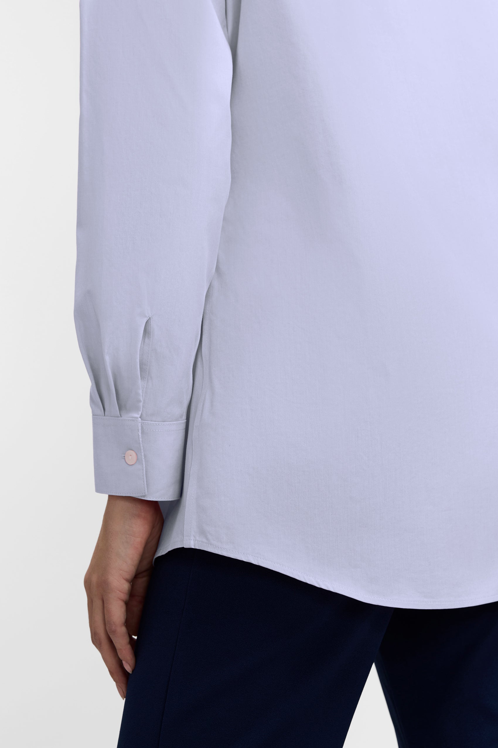 Back view of the Cici No Iron Pinpoint Long Sleeve Tunic showing the finished hem and the buttoned cuff of the sleeve #color_blue wave