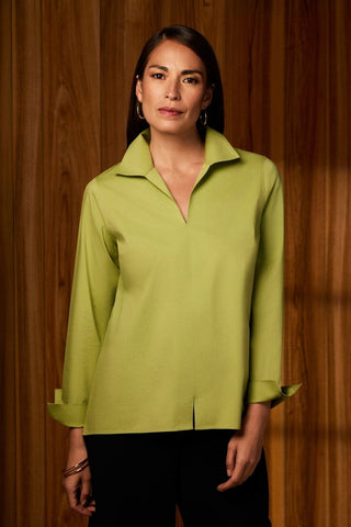 Woman in front of a wooden panel wearing the lightweight no iron Agnes long sleeve shirt in #color_celery