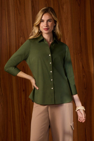 Women with hand on hip wearing the Mary No Iron Stretch 3/4 Sleeve Shirt in front of a wooden background #color_basil