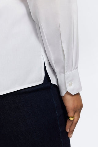 Close up view the the sleek arm cuff and the crisp pleats on the sleeve #color_white